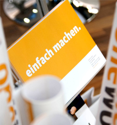 Infomaterial auf der tekom, Postkarte im Mittelpunkt mit "Einfach machen."