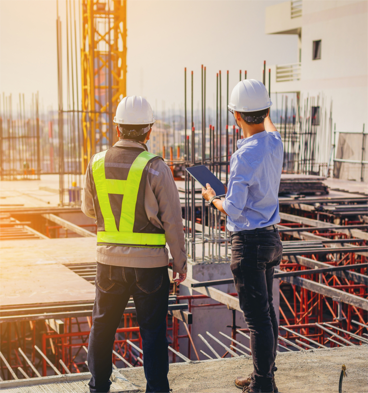 Zwei Bauarbeiter auf einer Baustelle, sie diskutieren den Baufortschritt.