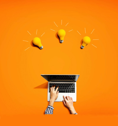 Tipps für die Softwarelokalisierung; Hände an einem Laptop mit 3 Glühbirnen darüber vor einem orangen Hintergrund