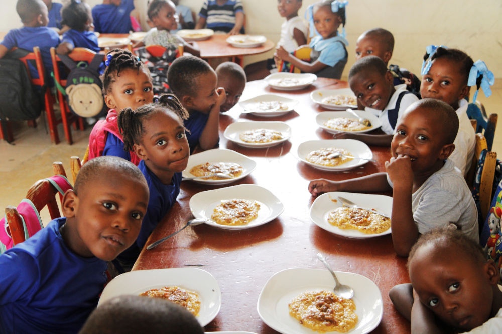 weihnachtsspende-nph-kinderhilfe-lateinamerika-2025-kinder-1 Weihnachtsspende nph Kinderhilfe Lateinamerika e. V. ; schwarze Kinder sitzen am Tisch mit gefüllten Tellern vor sich und schauen in die Kamera