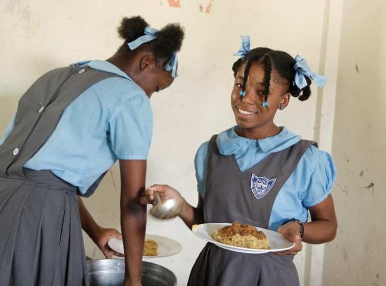 weihnachtsspende-nph-kinderhilfe-lateinamerika-2025-kinder-2 Weihnachtsspende nph Kinderhilfe Lateinamerika e. V. ; zwei schwarze Mädchen in Schuluniformen schöpfen sich Essen auf ihre Teller